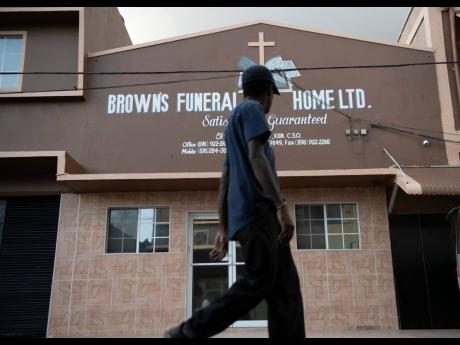 A commuter walks past Brown’s Funeral Home on North Street in Kingston yesterday. The building was raided by the police and boxes of medical and other supplies seized. 