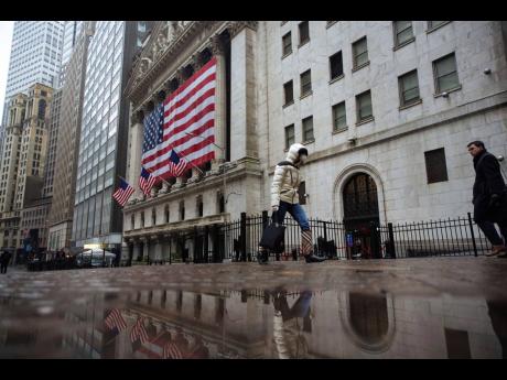 
A pedestrian, wearing a surgical mask and gloves, walks past the New York Stock Exchange on Thursday, March 19, in New York.