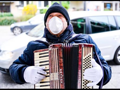 
A musician plays in mask and gloves at the ‘Isemarkt’ street market in Hamburg, Germany, on Friday, March 20. 