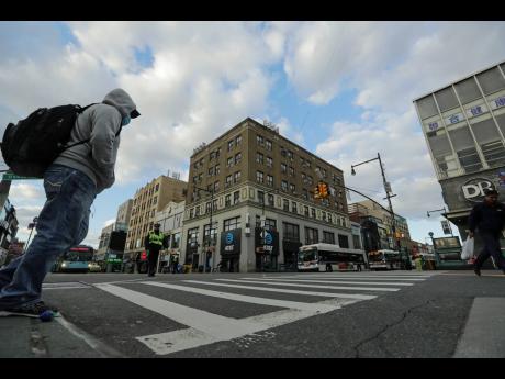 Pedestrians wear personal protective equipment as they cross Main Street on Wednesday, in the Flushing section of the Queens borough of New York. The new coronavirus causes mild or moderate symptoms for most people, but for some, especially older adults and people with existing health problems, it can cause more severe illness or death. 
