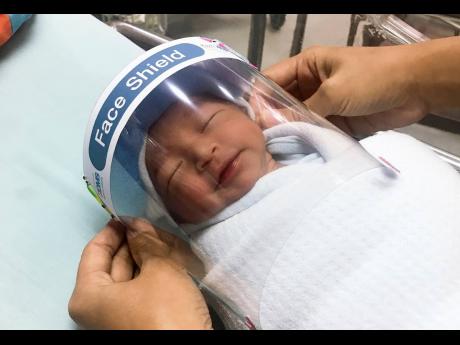In this  April 3 photo released by Paolo Hospital Samutprakarn, a nurse adjusts tiny face shield for a newborn baby to protect from new coronavirus at the newborn nursery of the hospital in Samutprakarn province, central Thailand. 
