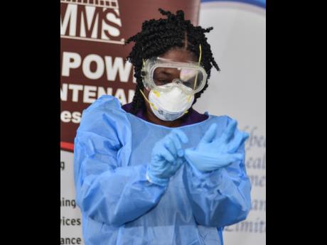 Credit: Kenyon Hemans/Photographer Yolande Sealy-Kerr, manager of the Spanish Town branch of Manpower and Maintenance Services Group Ltd, demonstrates how to properly remove protective gear during a coronavirus prevention workshop at Spanish Court Hotel on Thursday, March 5.