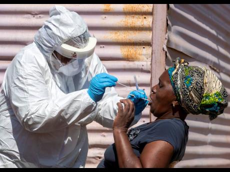 A woman opens her mouth for the health worker to collect a sample for coronavirus testing during the screening and testing campaign aimed to combat the spread of 
COVID-19 at Lenasia South, Johannesburg, South Africa, on Tuesday, April 21. 