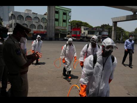 A senior police officer applauds as Disaster Response Force personnel arrive to disinfect a containment zone during lockdown to prevent the spread of new coronavirus in Hyderabad, India, Sunday, April 26, 2020. A monthlong restrictions in this country of 1.3 billion people have been eased somewhat by allowing neighbourhood shops to reopen and manufacturing and farming activities to resume in rural areas to help millions of poor daily wage earners. 