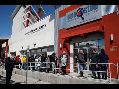 In this March 17, 2020 file photo, people wait in line for help with unemployment benefits at the One-Stop Career Center in Las Vegas. 