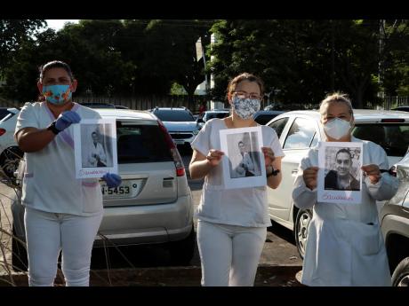 Health professionals hold up photos of people they say were their colleagues who died of COVID-19, as they protest outside ‘Pronto Socorro 28 de Agosto’ Hospital in Manaus, Brazil, yesterday. 