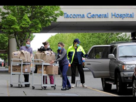 J.D. Elquist (right), of the Downtown Tacoma Partnership, delivers meals to workers at Tacoma General Hospital in Tacoma, Washington, Wednesday, April 29, 2020. The delivery was part of the organisation’s ‘Hero Meals’ project, which collects donations from the public to purchase meals from restaurants that are then given to healthcare workers, first responders, and other essential workers in the city during the coronavirus outbreak. 