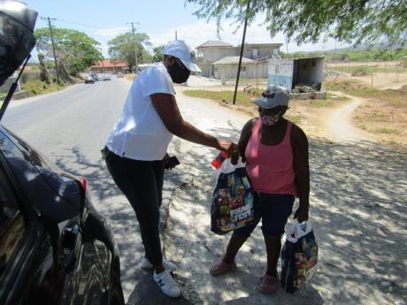 A member of the Kiwanis Club of St Thomas gives care packages to a resident on Friday.