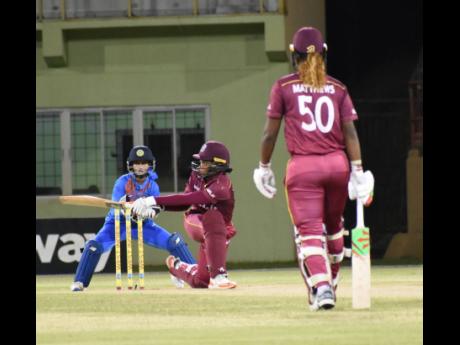 Windies Women’s Stacy-Ann King (centre) plays a shot while teammate Hayley Matthews (right) and India Women wicketkeeper Taniya Bhatia look on, during a Twenty20 International game at Providence, Guyana, on Thursday, November 14, 2019.