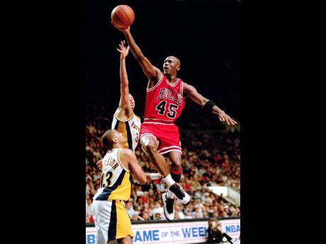 In this file photo from March 1995, Chicago Bulls guard Michael Jordan (45) flies to the hoop over the Indiana Pacers’ Reggie Miller and Mark Jackson (left) during an NBA game in Indianapolis, Indiana. 