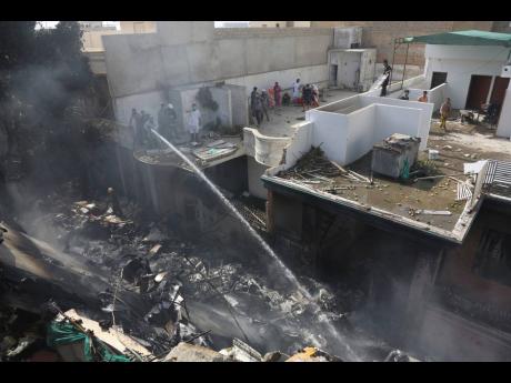 Fire brigade staff try to put out fire caused by plane crash in Karachi, Pakistan, on Friday, May 22. The passenger plane carrying nearly 100 passengers and crew crashed near Karachi's airport. 