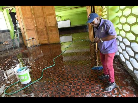Maintenance staff at Kingston Technical High School cleaning the floors to prepare for the reopening of school. Health officials in western Jamaica have voiced concerns about the prepardeness of the schools in their region as they reopen today, Monday, Jun
