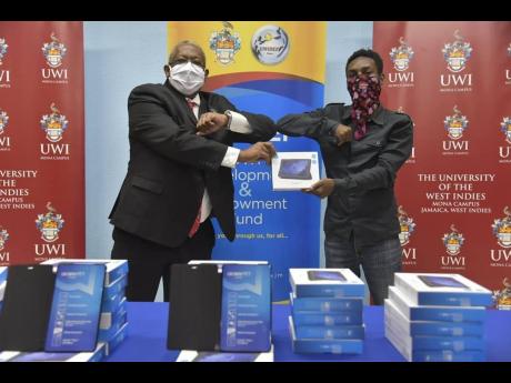 Credit: Principal of The University of the West Indies, Professor Dale Webber (left), hands over a recently donated tablet to a student.