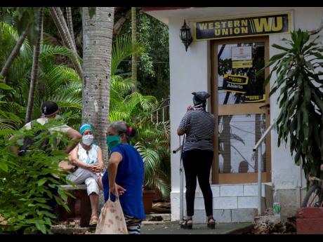 People stand outside a Western Union in the Vedado neighbourhood of Havana, Cuba, on Friday, June 12.