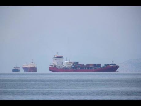 A cargo ship approaches the port of Piraeus as other ships are anchored near Athens, Greece, on Tuesday, May 26.