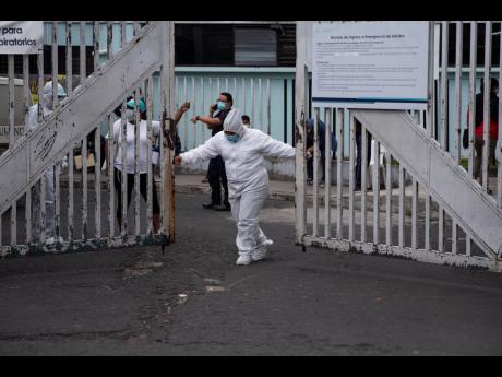 A health worker in protective gear to protect himself from COVID-19 closes the principal door of the coronavirus unit at San Juan de Dios Hospital in Guatemala City on Tuesday.  