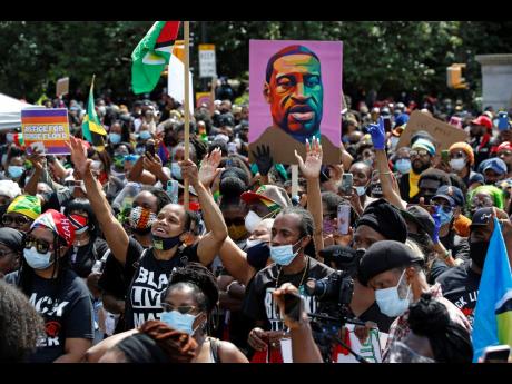 People inspired by a speaker raise their hands during a Caribbean-led Black Lives Matter rally at Brooklyn’s Grand Army Plaza in New York City on Sunday, June 14, 2020.
