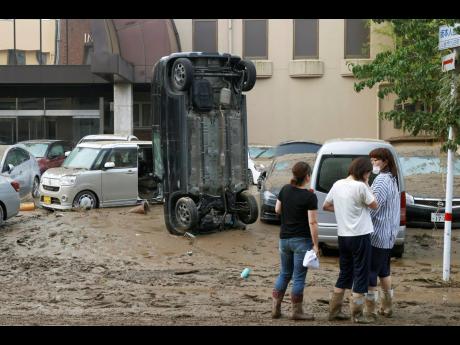 A car stands vertically on a muddy road after being washed away by flood, in Hitoyoshi, Kumamoto prefecture, southwestern Japan, Sunday, July 5, 2020. Heavy rain in the Kumamoto region triggered flooding and mudslides Saturday and left dozens still being s