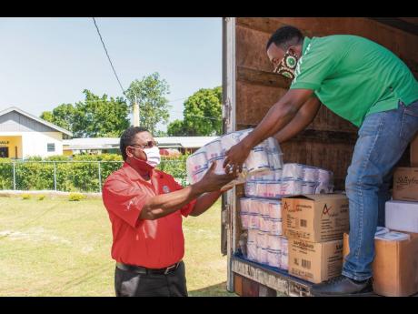 RUBiS Energy Jamaica Limited’s Human Resource Manager Donnovan Dobson (left) helps to offload personal care items that were donated to the Santa Cruz Infirmary in St Elizabeth on July 2 as part of the organisation’s efforts to assist in preventing the 