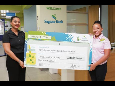Marie Dowdie (left), assistant branch manager, Sagicor Bank Jamaica Liguanea branch, presents a symbolic cheque to 11-year-old Imani-Leigh Hall, founder of the ILAH’s Lemon-Aid Stand for Kids Foundation, during a visit to the branch on July 8. The donati