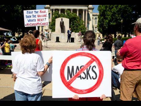 Protesters listen to William Kelly, host of the ‘Citizen Kelly Show’, as he speaks about suing Governor J.B. Pritzker over COVID-19 restrictions during the ‘Million Unmasked March’ at the Illinois State Capitol on Saturday, July 25, in Springfield,