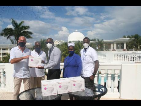 Enrico Pizzoli (left), general manager of Grand Palladium Hotel, presents one of six nebuliser machines to Carlington McLennon (centre); CEO of the Noel Holmes Hospital. Looking on are Leroy Peart (second left), president of the Grand Palladium Hotel Staff