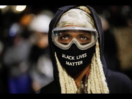 A protester wears a mask and goggles outside the Mark O. Hatfield United States Courthouse during a Black Lives Matter protest on Friday, July 24, 2020, in Portland, Oregon. 