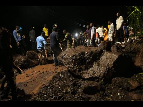 Residents work into the night on Sunday to remove a huge boulder that blocked a section of the main road between Papine and Gordon Town in St Andrew as heavy rains associated with the outer bands of Tropical Storm Laura pelted the country. Residents, motor