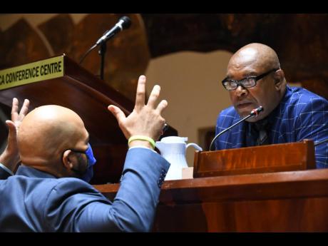Deputy Mayor of Kingston Winston Ennis (right) listens to Councillor Andrew Bellamy during Tuesday's sitting of the Kingston and St Andrew Municipal Corporation at the Jamaica Conference Centre in Kingston.