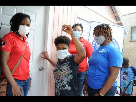 Twenty-one-year-old paraplegic student Tiffany Thomas excitedly jingles the keys to her new starter home, courtesy of Salada Foods in partnership with Food For The Poor Jamaica, during a handing over ceremony last month. Marking this historic moment are Ta
