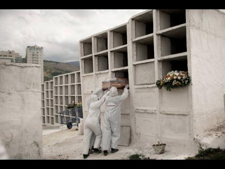 Credit: Silvia Izquierdo Cemetery workers place the coffin containing the remains of Jose de Arimateia, 65, who died from COVID-19 complications, into a niche at the municipal cemetery in Nova Iguacu, Brazil..