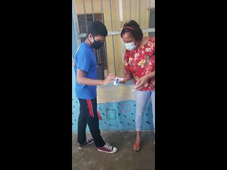 Matthew Wilmot (left) and Angelyn Hayes, principal of the Winston Peddie Basic School, test a thermometer donated to the institution. 