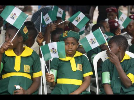 School children wave flags during the 54th anniversary in 2014 celebrations of Nigerian independence in Lagos, Nigeria.  