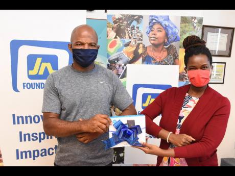 Onyka Barrett Scott (right), general manager of the JN Foundation, presents one of the 15 tablets donated to Woodford Primary School to Cedric Pascoe, president of the Woodford Community Action Group.