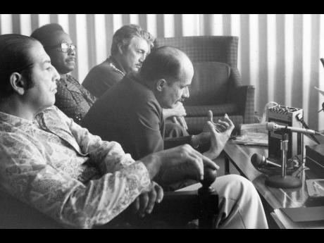 In this March 1977 photo, Annibel Villela, executive secretary for Economic and Social Affairs in the General Secretariat of the Organization of American States (at mike), speaks to the press in an airport interview; Others from left are Dr. Sergio Vellozo