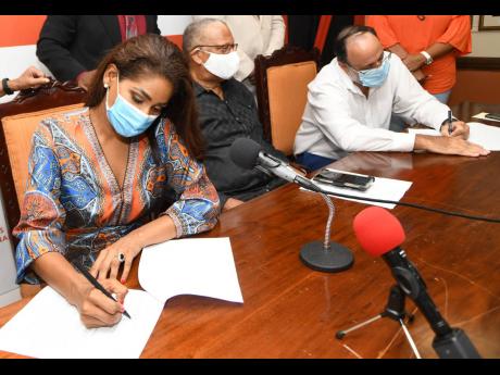 Credit: Rudolph Brown/Photographer People’s National Party presidential contenders Lisa Hanna and Mark Golding signing a code of conduct for the election campaign last week as party President Dr Peter Phillips looks on.