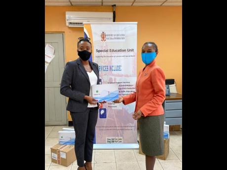 Daenia Ashpole, managing director of Day and Night Beauty Salon and Spa, hands over 25 tablets to Marcia McDonald, principal of Carberry Court Special School.