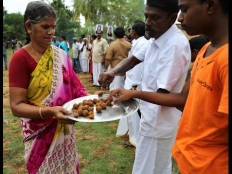 Credit: AP An Indian woman distributes sweets among villagers during celebrations for the victory of US Vice-President-elect Kamala Harris in Painganadu.
