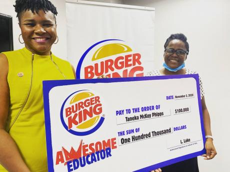Burger King’s head of marketing, Sabrena McDonald Radcliffe (left), presents teacher Taneka McKoy Phipps with a cheque for $100,000 to assist students in her community using the traditional blackboard and chalk.  A teacher at Union Gardens Infant School 