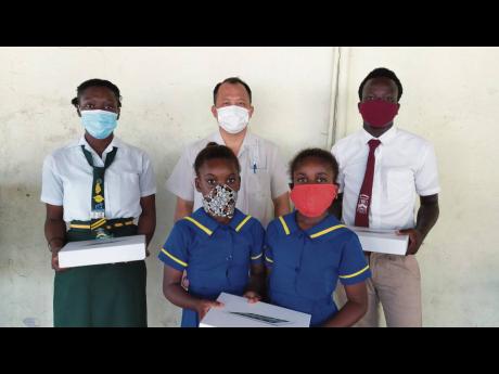 Businessman Steven Liao with four of the students presented with tablets on the grounds of the May Pen Primary School in Clarendon on Wednesday. More than 100 students were given tablets under the James and Friends Education Programme. 