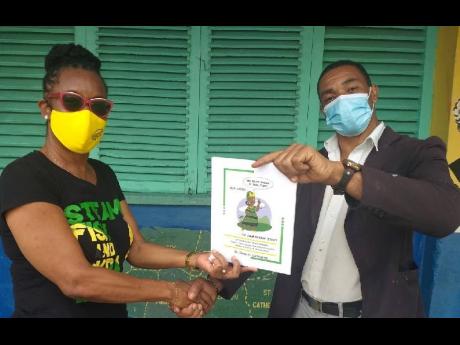 
Dr Dawn Lemonious (left) presents a copy of her book, ‘Mi Have Sinting Fi Tell Yuh’, to Alanzo Rose, principal at Ulster Spring Primary School in Trelawny.