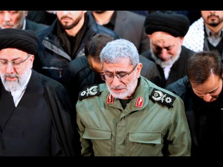 In this photo released by the official website of the Office of the Iranian Supreme Leader, Gen Esmail Ghaani, newly appointed commander of Iran’s Revolutionary Guards Quds Force, weeps while praying over the coffin of the force’s previous head Gen Qas