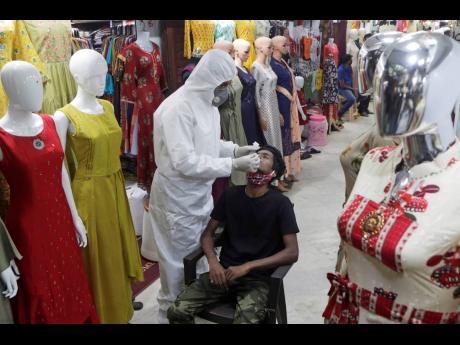 Credit: The Associated Press A health worker takes a swab sample to test for COVID-19 inside a garment market in Mumbai, India yesterday.
