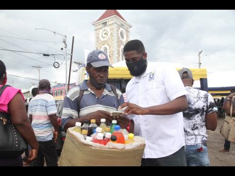 Credit: Nathaniel Stewart/Photographer Jason Williams of the Universal Service Fund assists Mark ‘Juici’ Henry to connect to the Internet using the free public Wi-Fi during its launch in May Pen, Clarendon, yesterday.