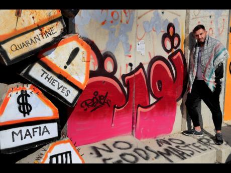 Khaldoun Jaber, a Lebanese anti-government activist, stands beside the concrete wall that was installed by security forces to prevent protesters from reaching the parliament building in Beirut, Lebanon.