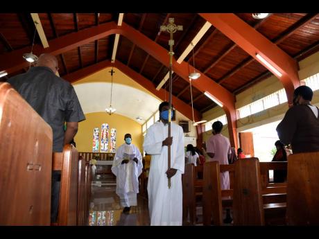 Sanjay Campbell leads his father, the Rev Sean Major-Campbell, out of Christ Church during the recessional at the end of a service paying respect to those who have been affected by HIV and AIDS. Like all churches that are subject to coronavirus restriction