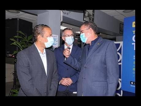 Minister of Energy Daryl Vaz (right) makes a point about the increased use of technology at the launch of the new MyJPS mobile app, designed to deliver convenience to customers.  Listening intently are JPS Chief Operating Officer Gary Barrow (left) and JPS