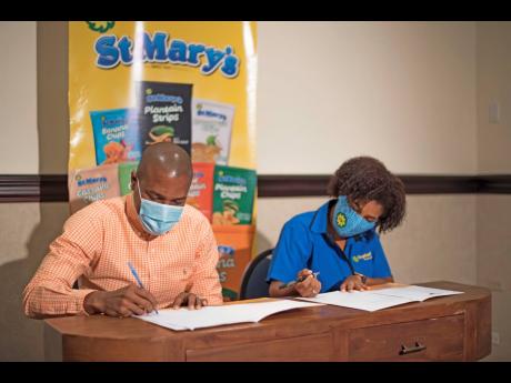 Professional Football Jamaica Chairman Chris Williams (left) and Jamaica Producers Chief Commercial Director Maya Johnston sign a partnership between both brands for the upcoming Jamaica Premier League at a press conference at The Jamaica Pegasus hotel in 