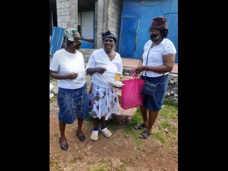 Credit: Photo by Cecelia Campbell-Livingston Two members of the women’s ministry present a care package and a meal to one shut-in.