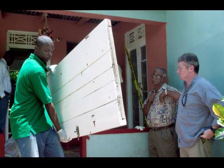 Credit: File A Scotland Yard detective overseeing the removal of items from the death house in Kraal, Clarendon, on June 3, 2003, a month after four people were killed there by a police team.